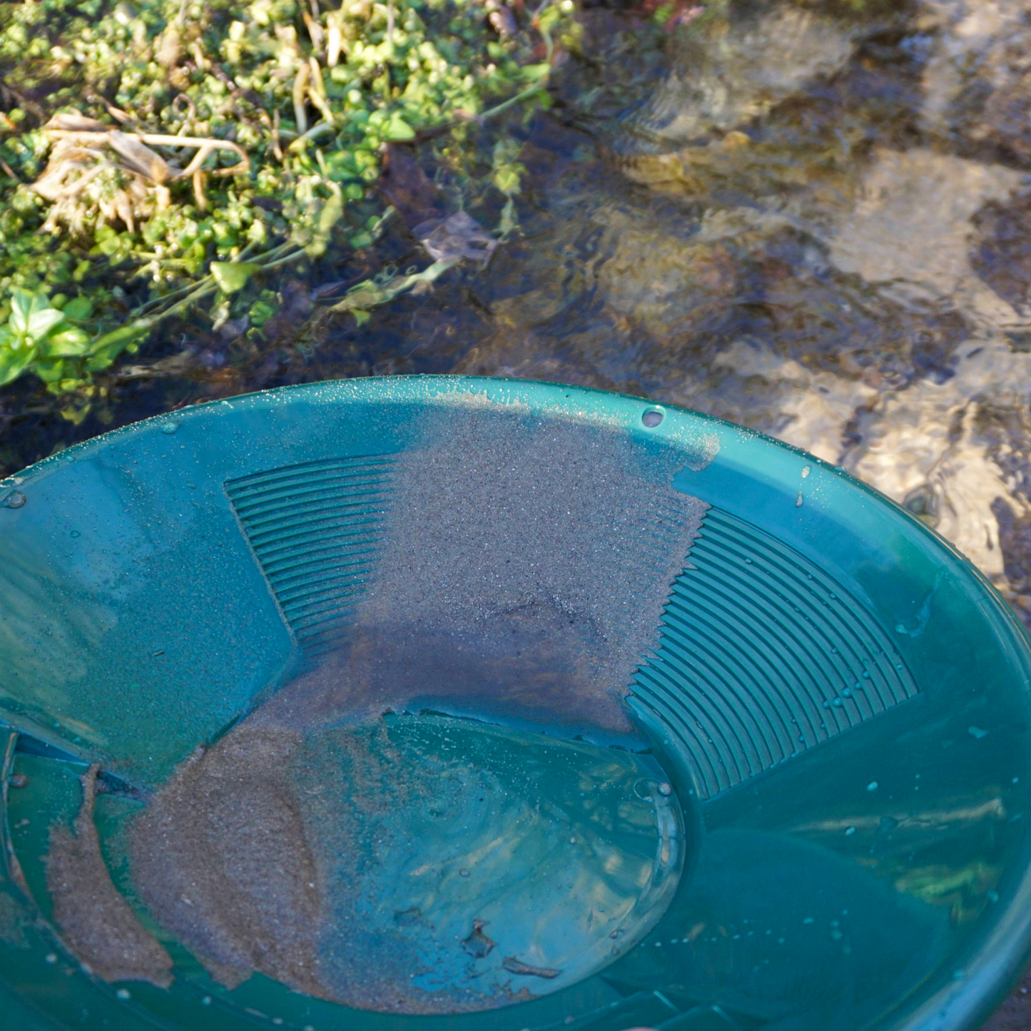 NubuClo gold panning pan in use for separating gold and sediment.

